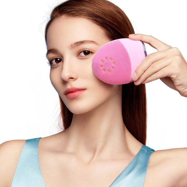 Femme utilisant brosse nettoyante électrique visage